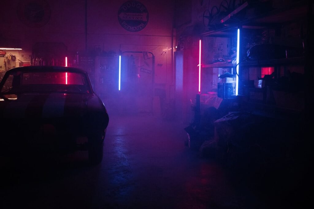 Moody garage interior featuring neon lights and a classic car silhouette amidst smoky ambiance.